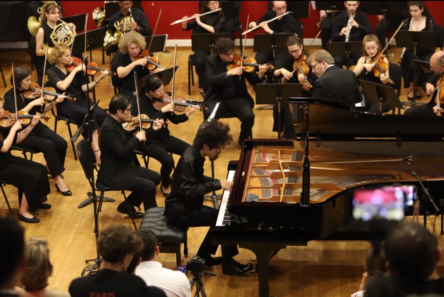 A young pianist performing a concerto with the festival orchestra